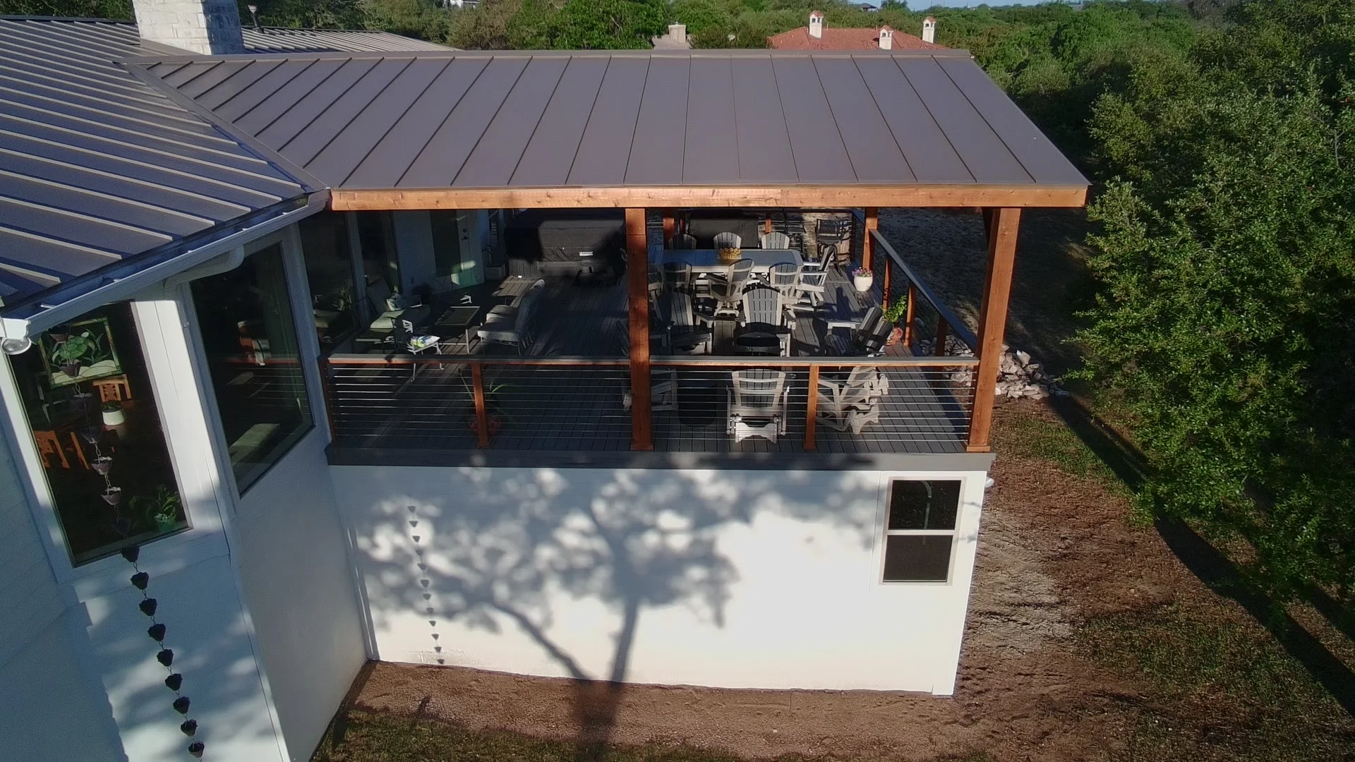 Second-story grey deck and brown metal patio cover attached to white Hill Country home near San Antonio
